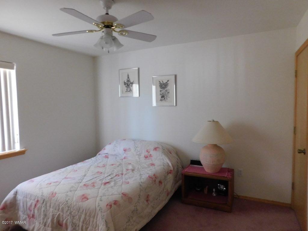 2749 Canyon Ridge Road Overgaard, AZ 85933 - Photo 23 of 25 a bedroom with a bed and a chandelier