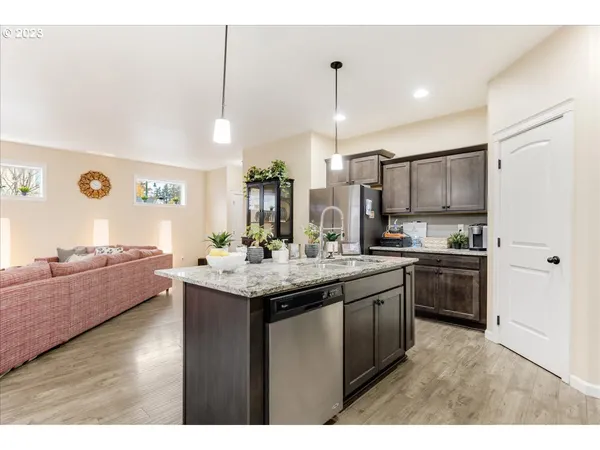 a kitchen with stainless steel appliances kitchen island granite countertop a sink a stove and a wooden floors