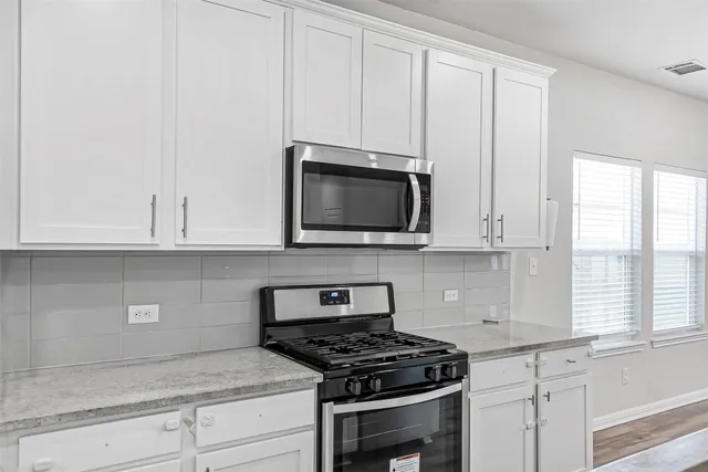 a kitchen with stainless steel appliances granite countertop white cabinets and a stove a oven with white countertops