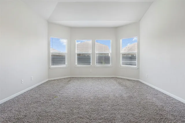 an empty room with chandelier fan and windows