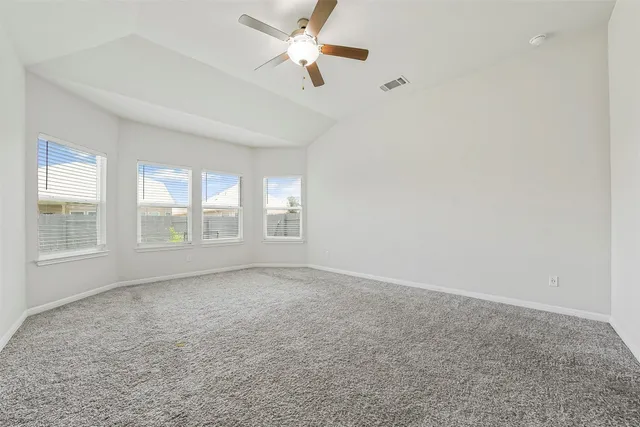 an empty room with chandelier fan and windows