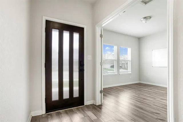 an empty room with wooden floor and windows