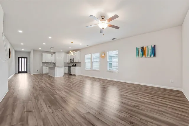 a view of an empty room with wooden floor and a window