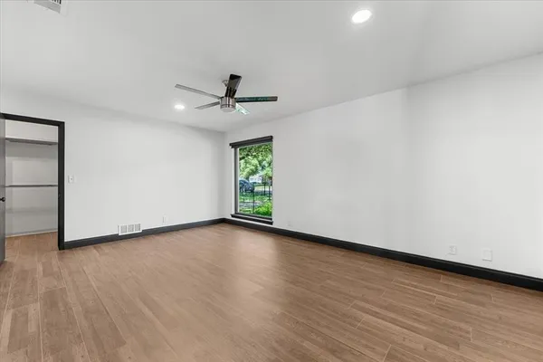 a view of empty room with wooden floor and fan