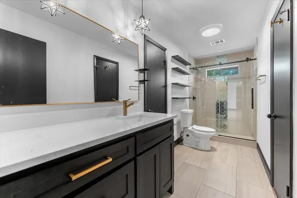 a bathroom with a sink a toilet a mirror and shower