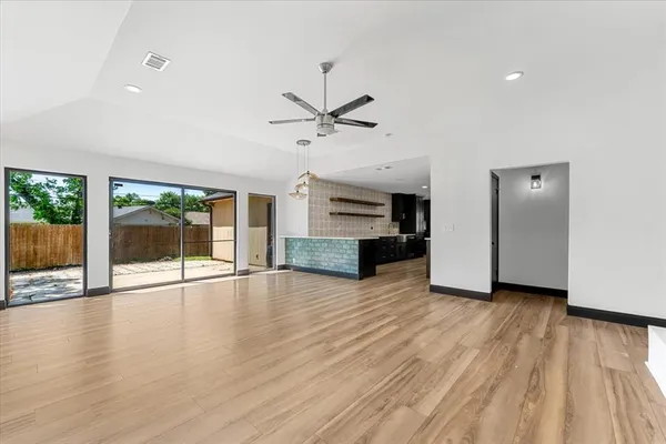 a view of an empty room with a kitchen and wooden floor