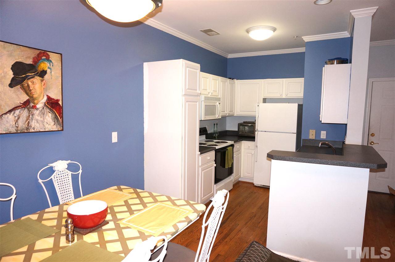 710 North Person Street, Unit 107 Raleigh, NC 27604 - Photo 11 of 21 a kitchen with stainless steel appliances a refrigerator a stove a dining table and chairs