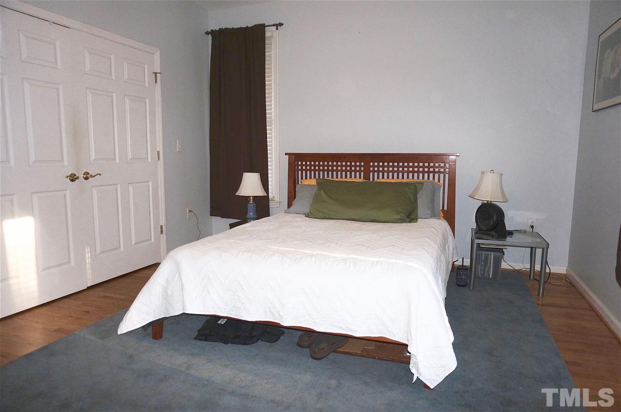 710 North Person Street, Unit 107 Raleigh, NC 27604 - Photo 16 of 21 a bedroom with a bed and wooden floor