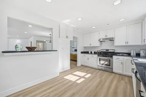 a kitchen with granite countertop white cabinets and white appliances