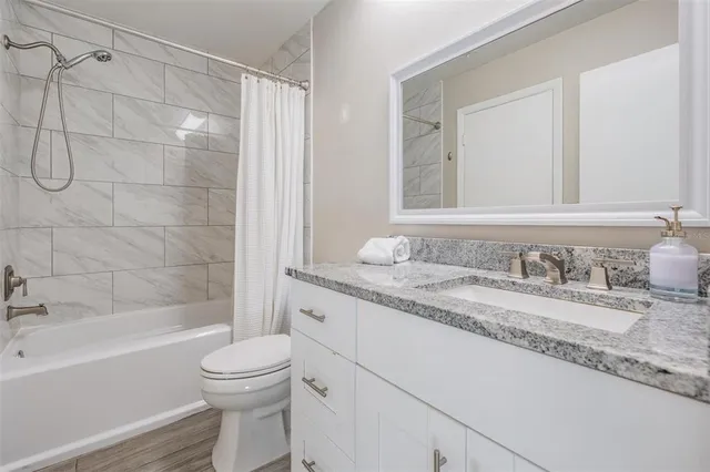 a bathroom with a granite countertop sink a toilet and shower