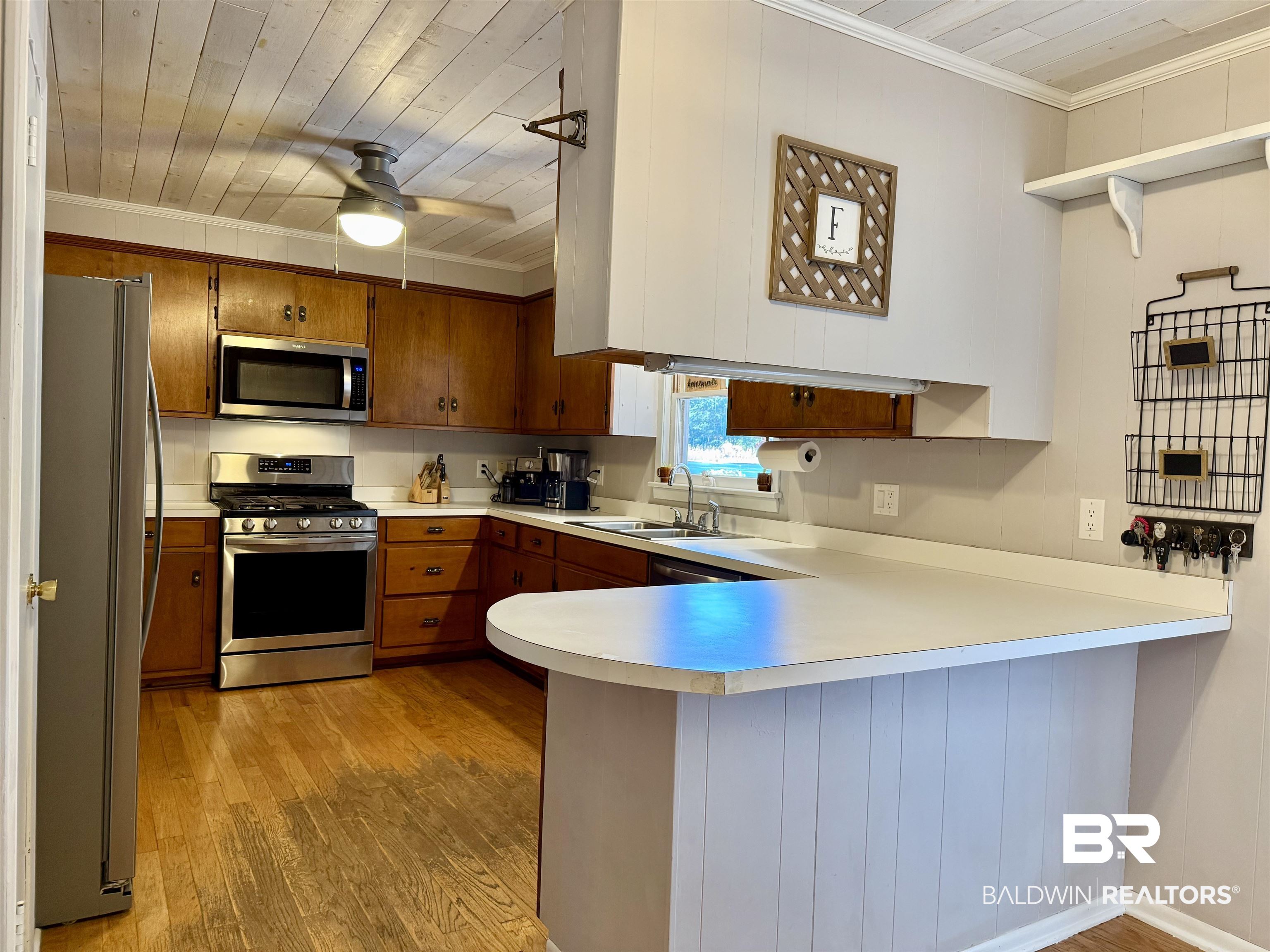 2785 Appleton Road Brewton, AL 36426 - Photo 14 of 28 Kitchen with brown cabinets, a peninsula, appliances with stainless steel finishes, light countertops, and light wood-type flooring