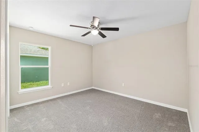 an empty room with a window and a fan