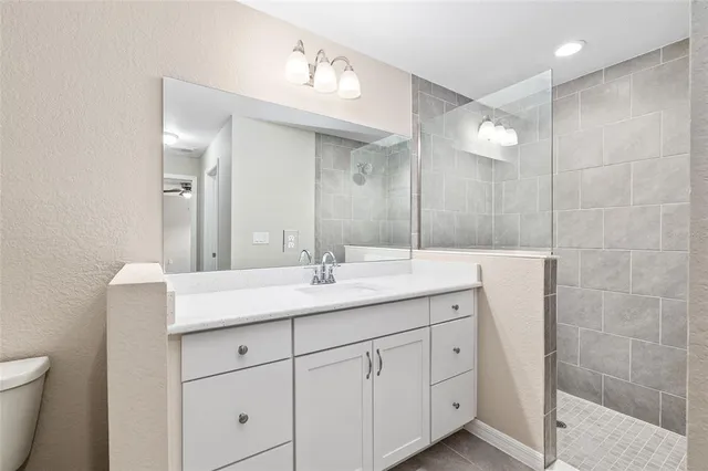 a bathroom with a granite countertop sink a toilet and a mirror