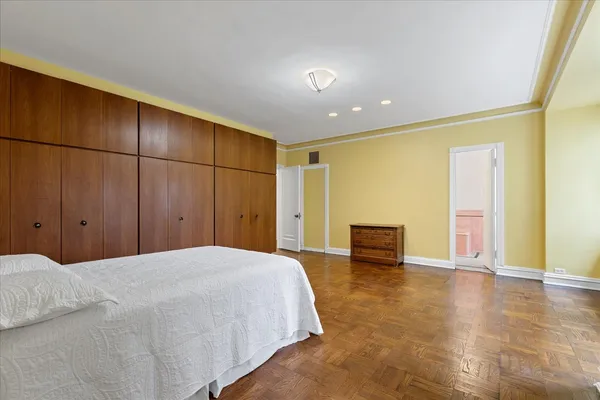 a spacious bedroom with a bed and wooden floor