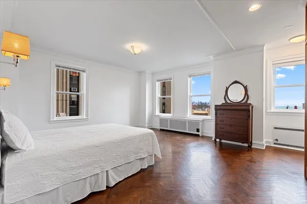 a bedroom with a bed and dresser with wooden floor