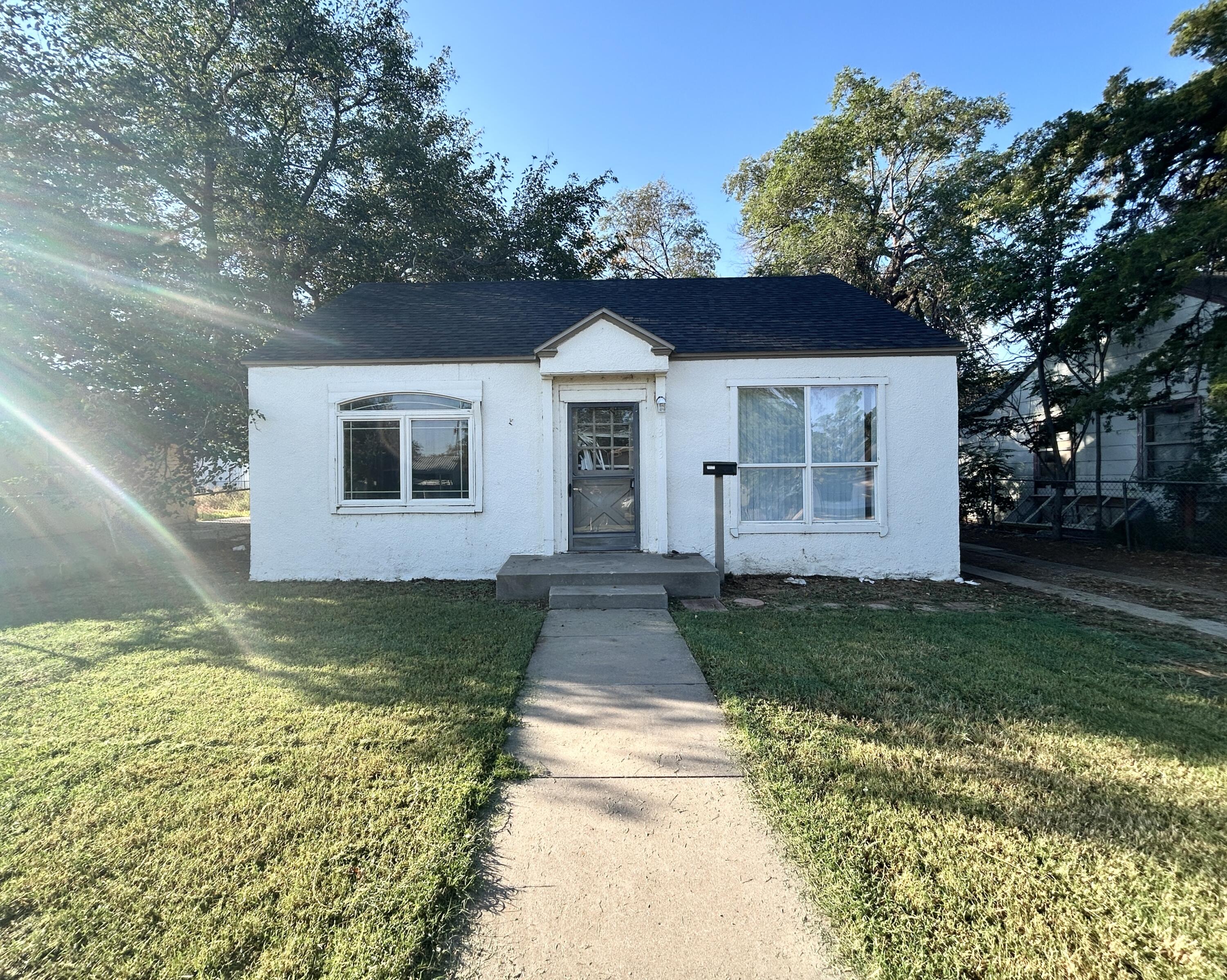 a view of a yard in front of a house with large trees