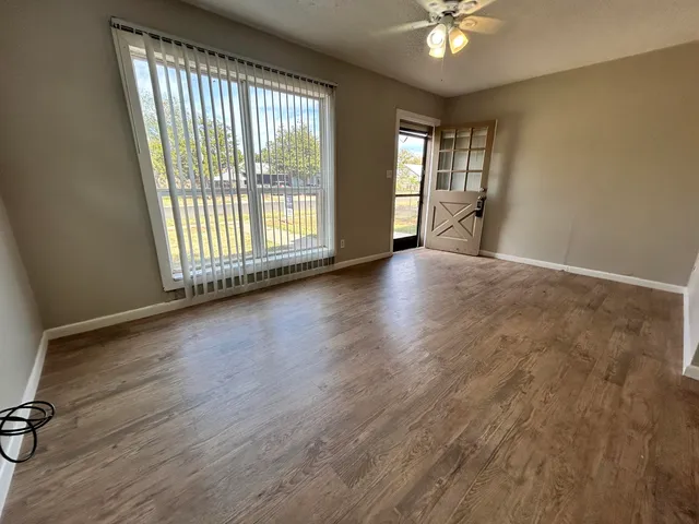 a view of an empty room with a window and wooden floor