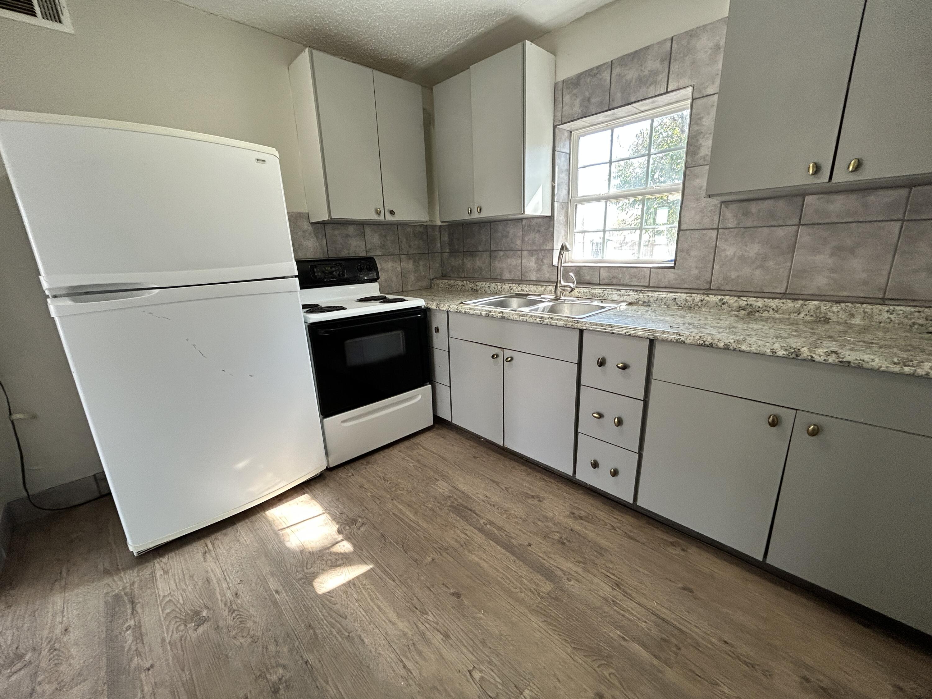 1313 25th Street Lubbock, TX 79411 - Photo 5 of 9 a kitchen with granite countertop white cabinets white appliances a sink and a window