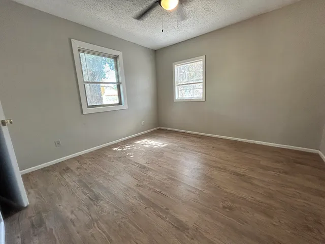 a view of an empty room with window and wooden floor