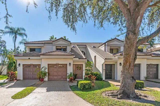 a front view of a house with a garden and a tree