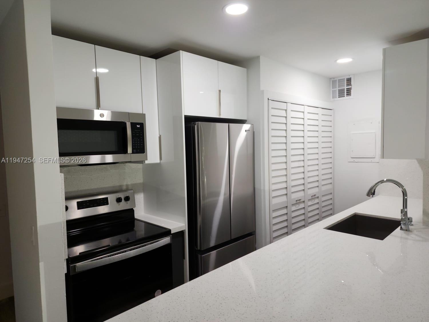 4545 Treehouse Lane, Unit H Tamarac, FL 33319 - Photo 2 of 18 a kitchen with a refrigerator and a sink
