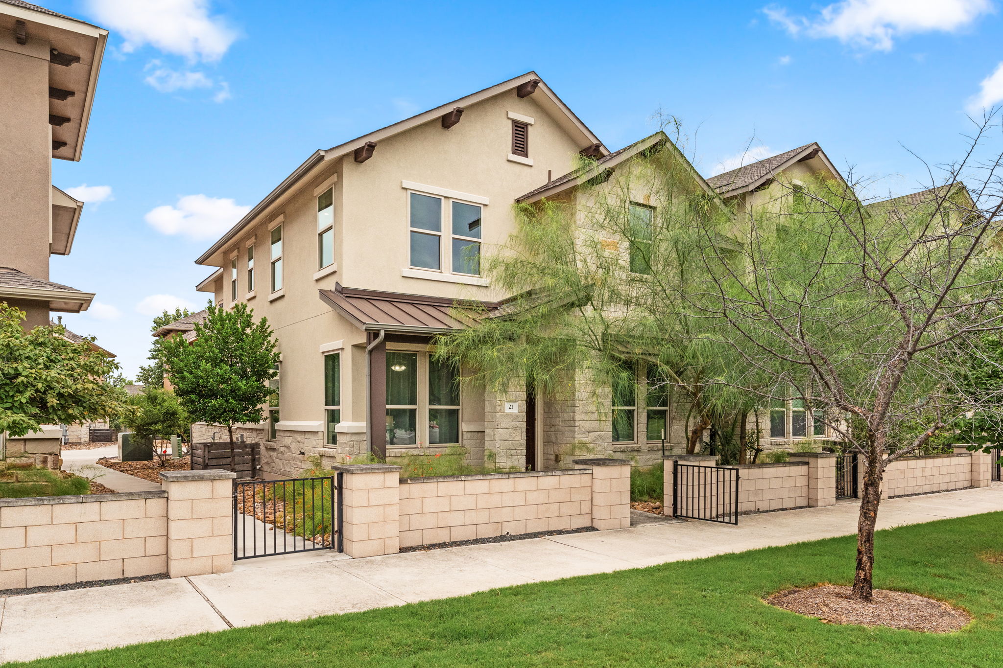 View of front of home with a gate, a standing seam roof, a metal roof, stone siding, and a fenced front yard