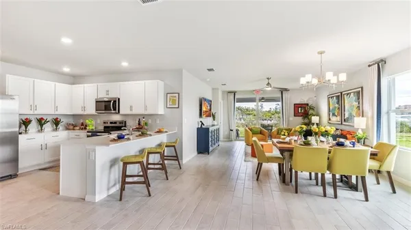a view of a dining room and livingroom with furniture wooden floor a rug a fireplace and a chandelier