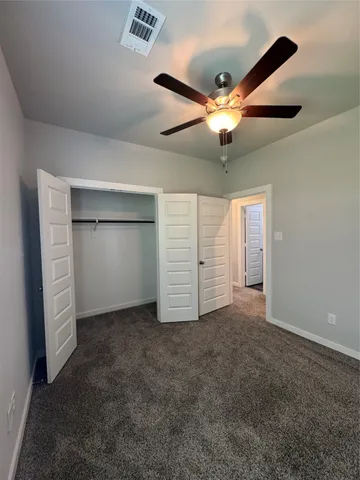 an empty room with closet and a ceiling fan