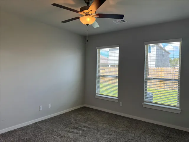 an empty room with windows and fan
