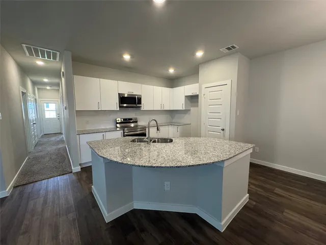 a kitchen with stainless steel appliances granite countertop a sink a stove a refrigerator and a oven