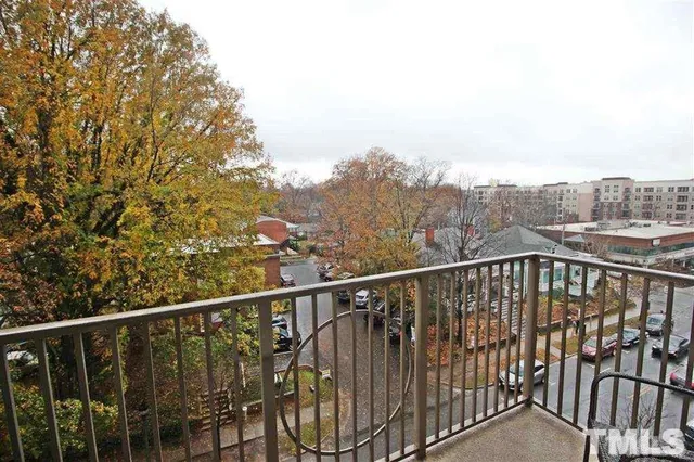 a view of a balcony with wooden chairs and iron fence