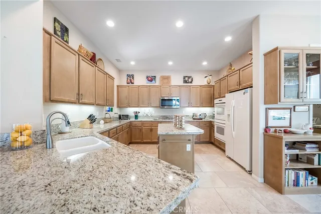 a room with stainless steel appliances kitchen island granite countertop a refrigerator and a sink