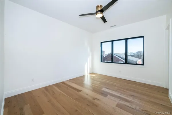 an empty room with wooden floor and ceiling fan