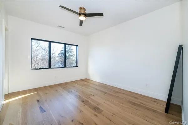 an empty room with wooden floor fan and windows