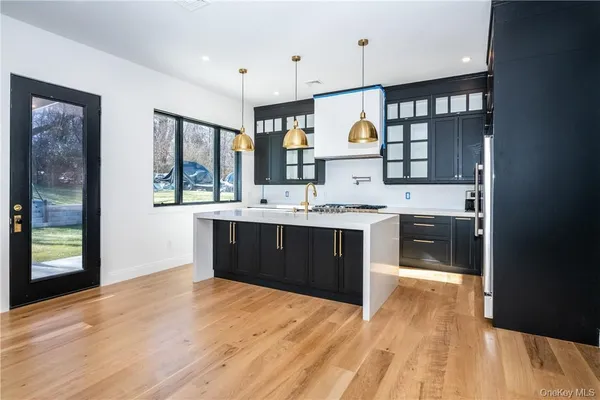a large kitchen with a sink wooden floor and a refrigerator