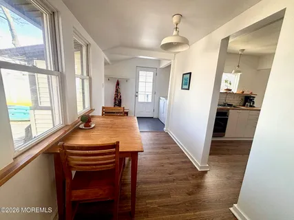 a dining room with wooden floor and large windows