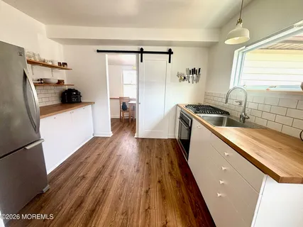 a kitchen with sink a refrigerator and wooden floor
