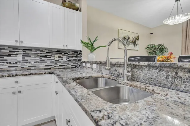 a kitchen with stainless steel appliances granite countertop a sink a stove and white cabinets