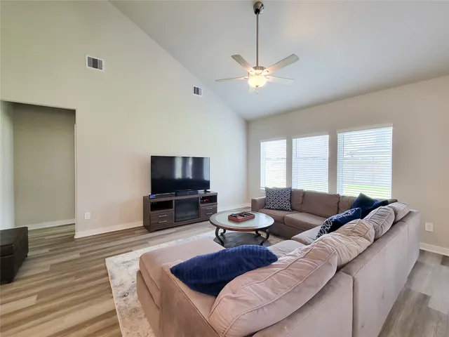 a living room with furniture a flat screen tv and a window