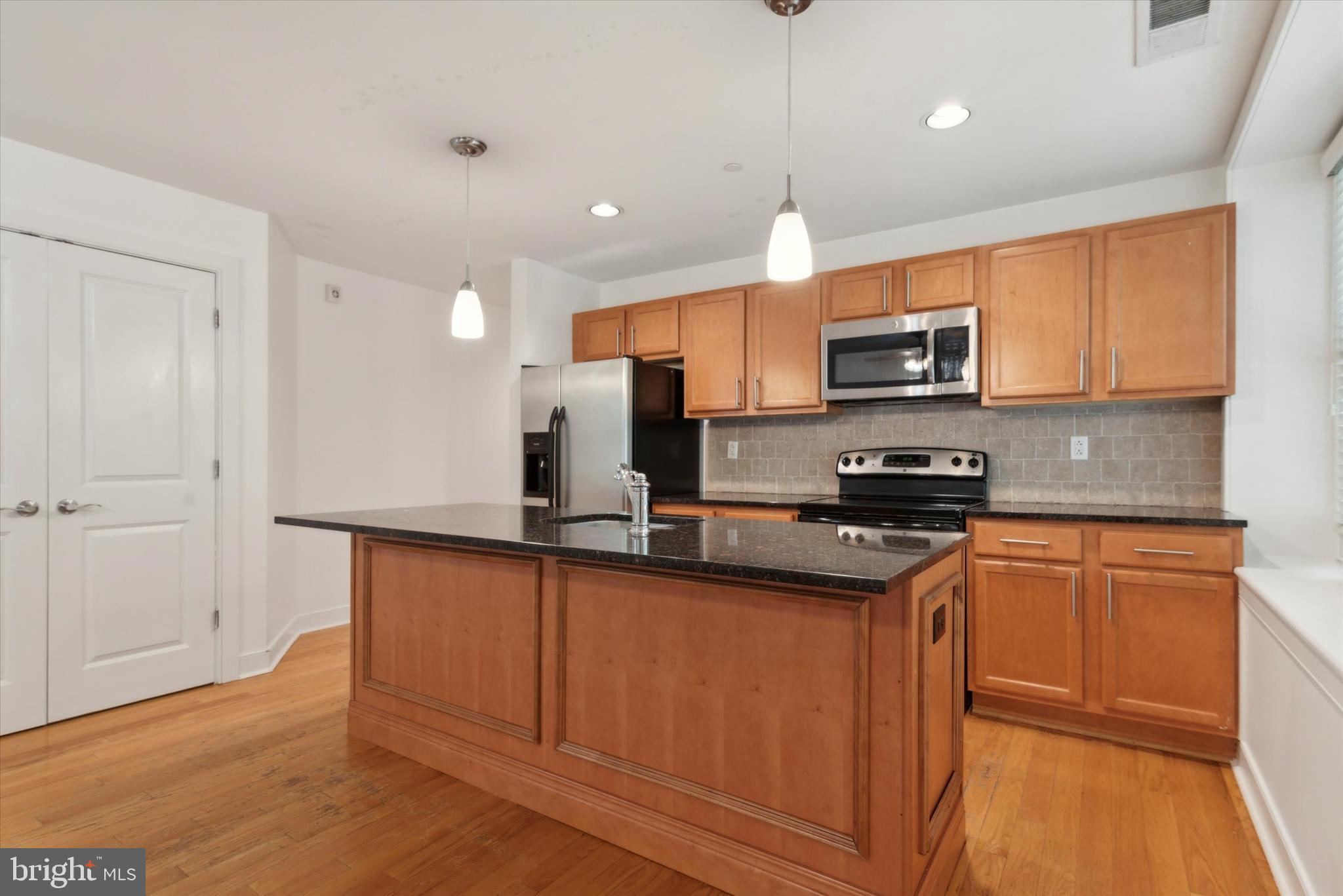 4300 Spruce Street, Unit A101 Philadelphia, PA 19104 - Photo 12 of 25 a kitchen with stainless steel appliances granite countertop a sink refrigerator and microwave