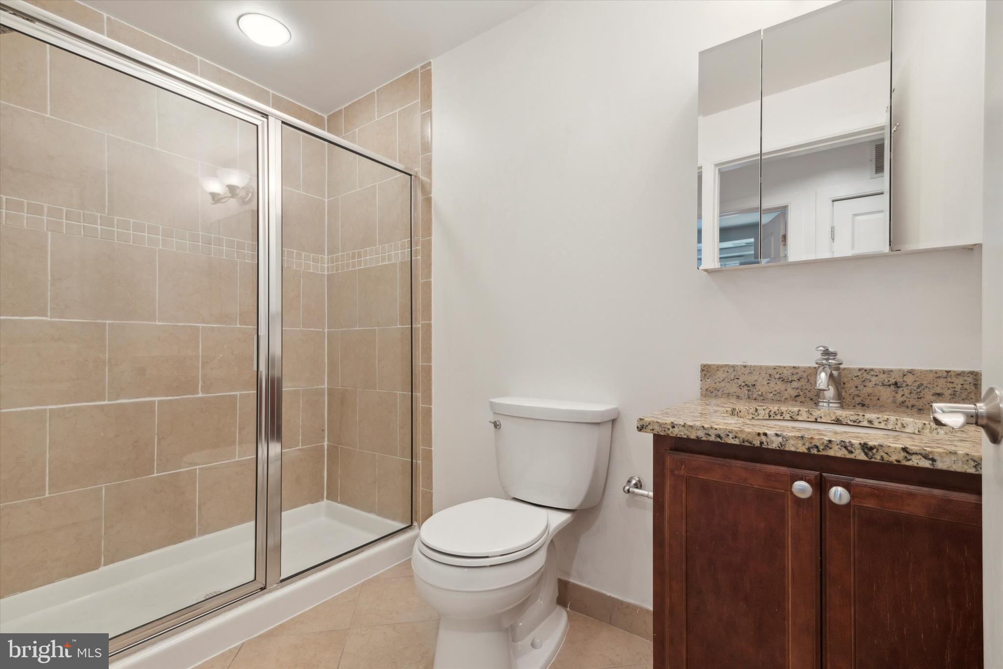 4300 Spruce Street, Unit A101 Philadelphia, PA 19104 - Photo 21 of 25 a bathroom with a granite countertop sink a toilet and shower