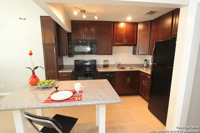 a kitchen with stainless steel appliances kitchen island granite countertop a sink a stove and refrigerator
