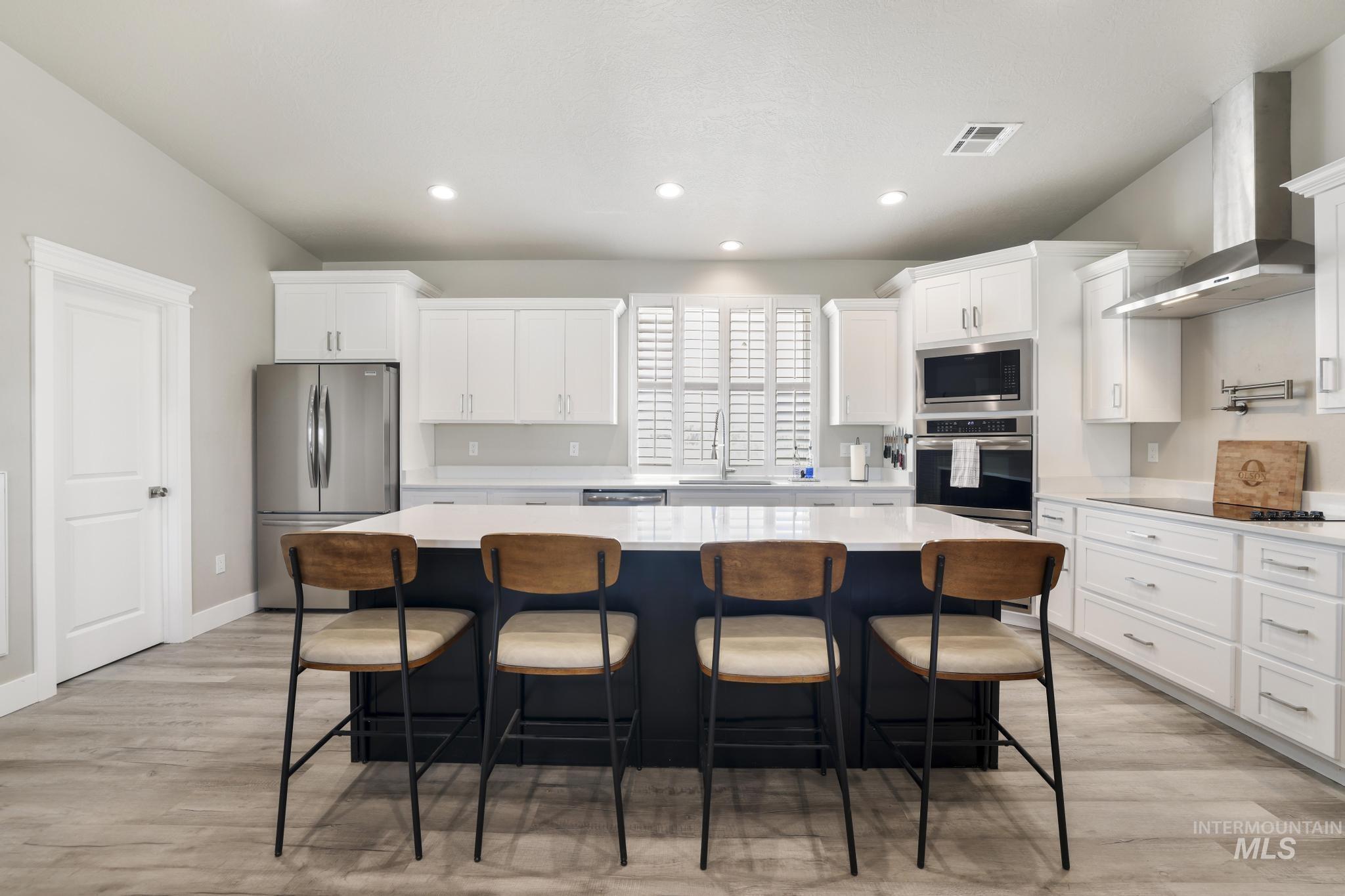 758 Cedar Crk Road Rogerson, ID 83302 - Photo 6 of 50 Modern kitchen featuring white cabinetry, a dark-toned island with a white countertop, stainless steel appliances, recessed lighting, and wood-finish flooring