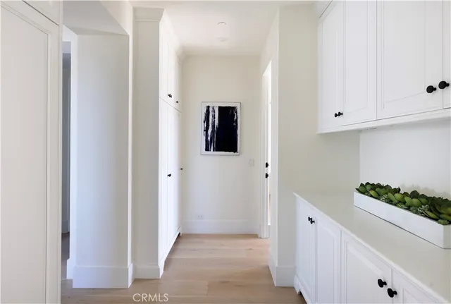 a view of a hallway with wooden floor and cabinet