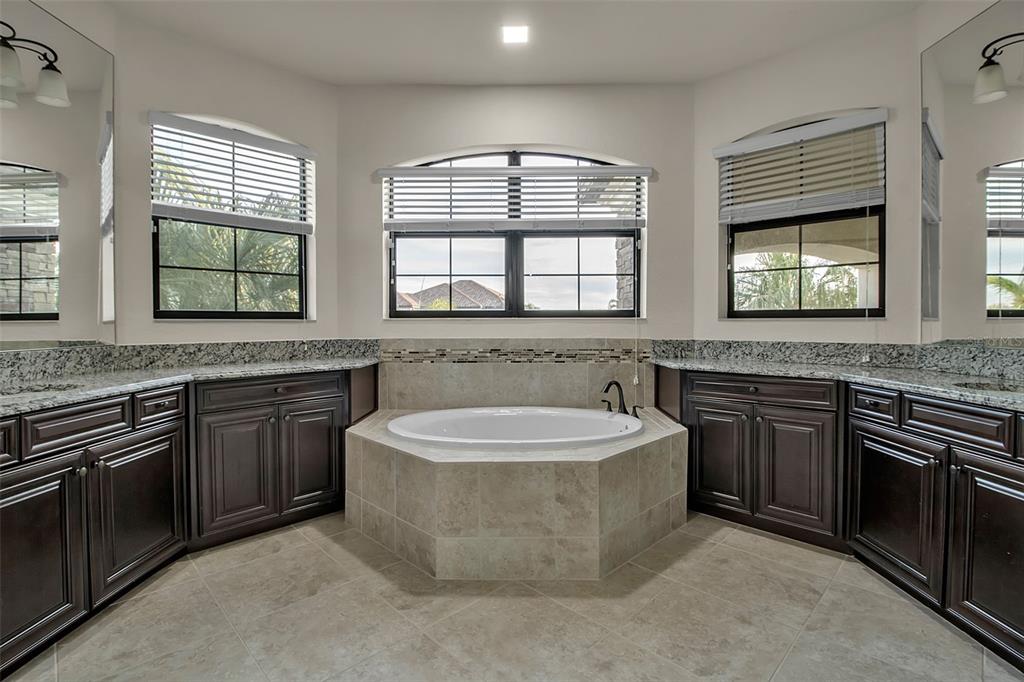 5609 Arnie Loop Lakewood Ranch, FL 34211 - Photo 29 of 64 a spacious bathroom with a granite countertop double vanity sink a mirror and a bathtub