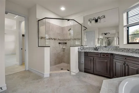 a bathroom with a granite countertop bathtub shower sink vanity mirror and toilet