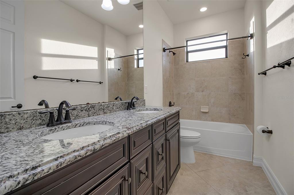 5609 Arnie Loop Lakewood Ranch, FL 34211 - Photo 41 of 64 a bathroom with a granite countertop sink a toilet and bathtub