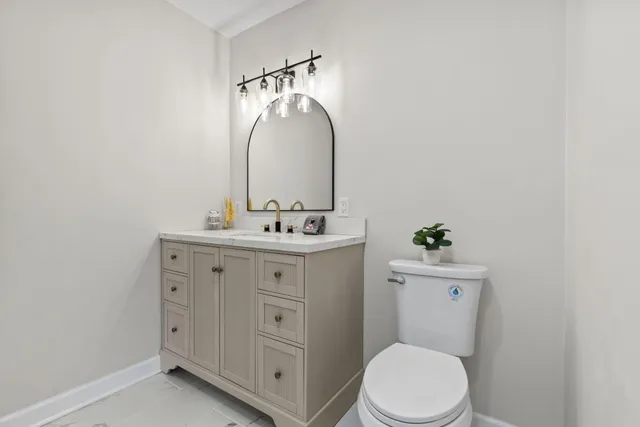 a bathroom with a toilet sink vanity and mirror