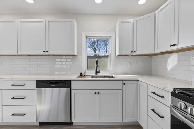 a kitchen with white cabinets and sink