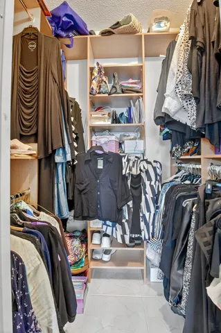 a view of walk in closet with clothes and shoes